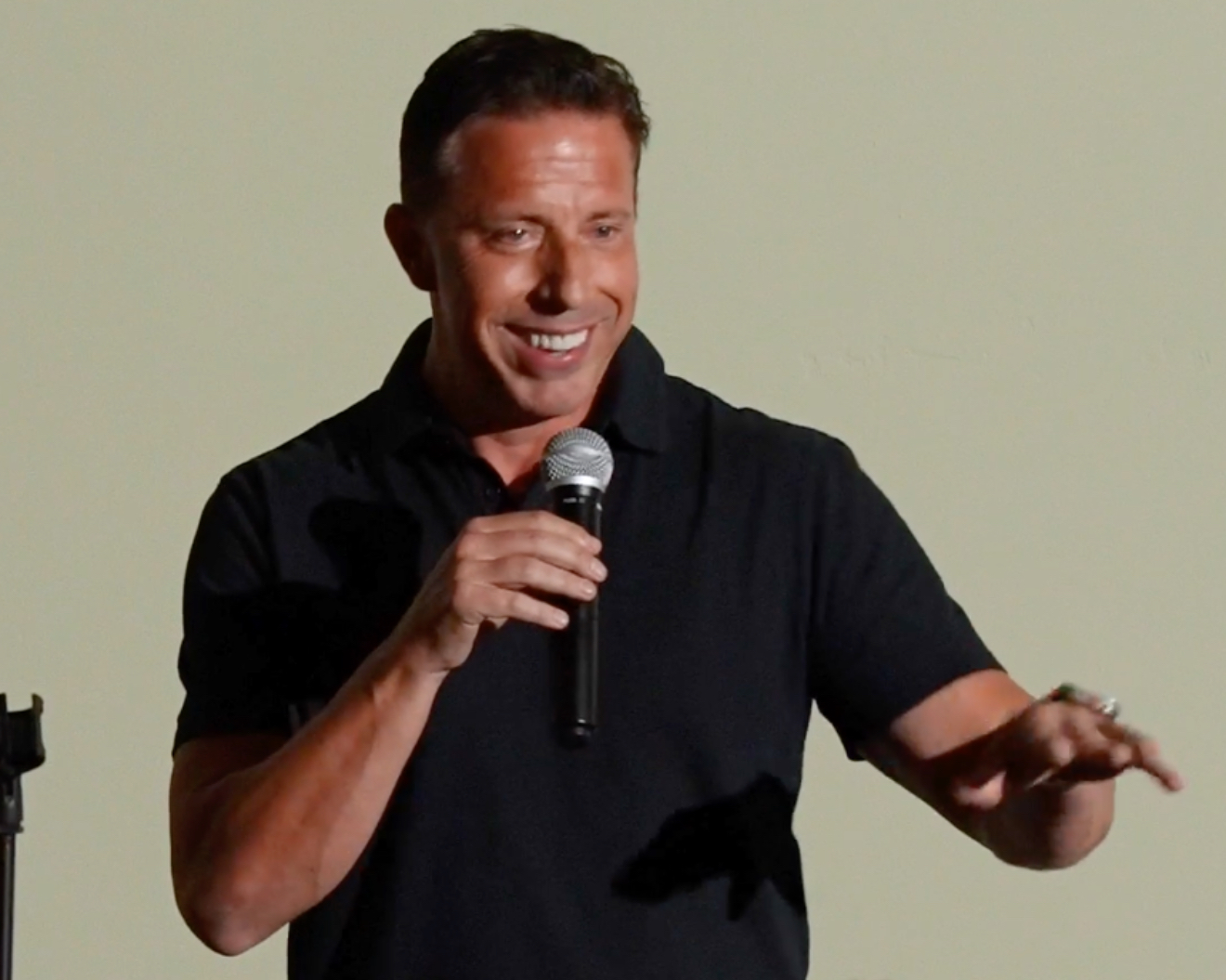 Aaron Bare laughing on stage with a microphone