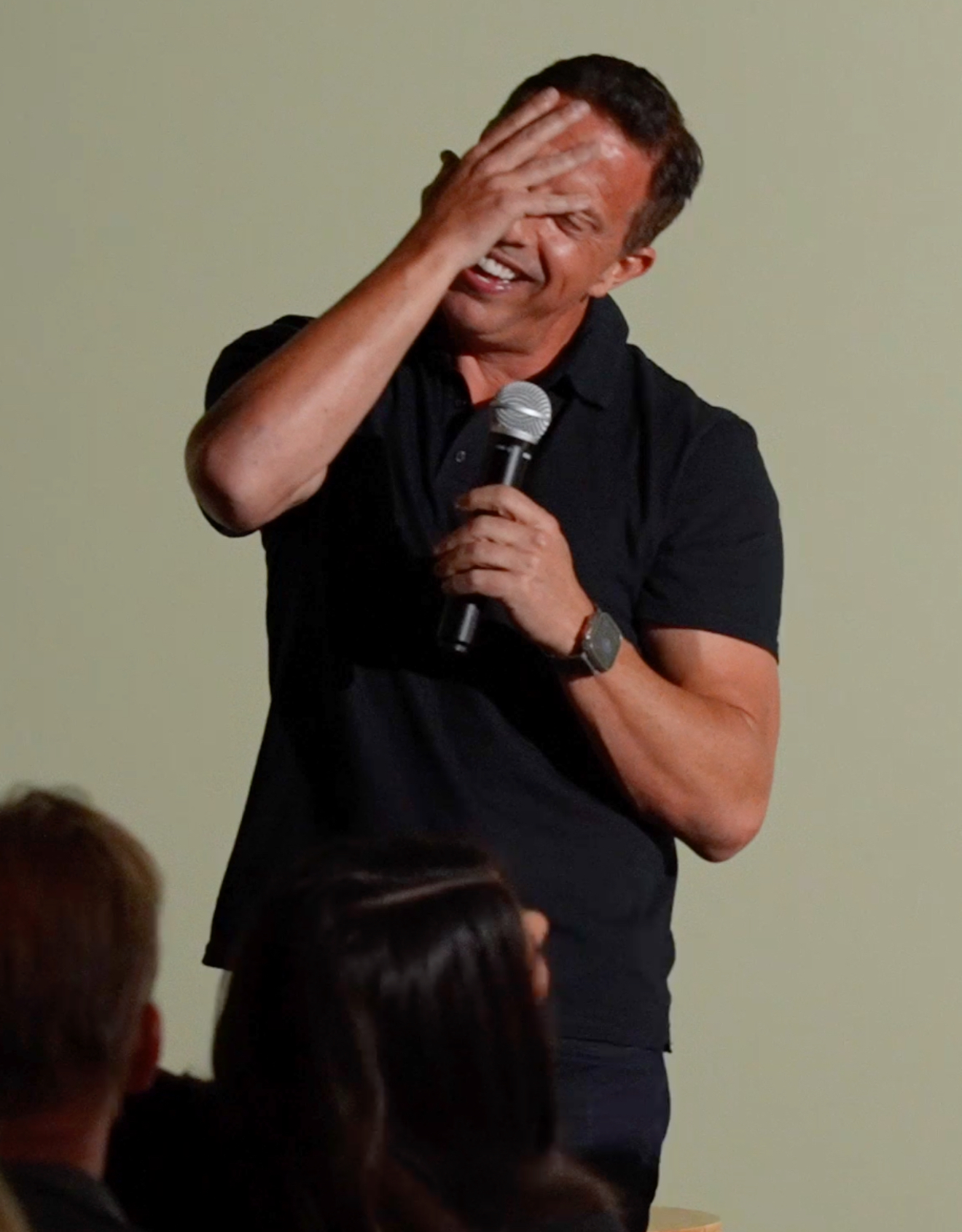 Aaron Bare covering his face laughing on stage